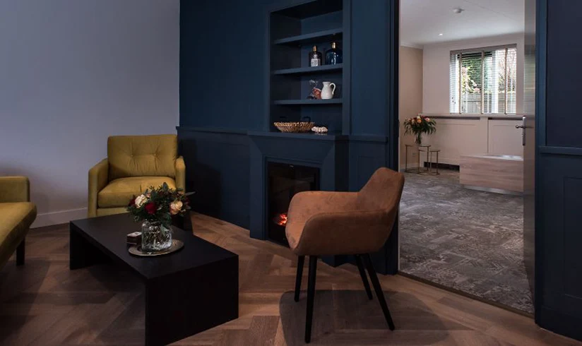 Kamer met een gele bank en fauteuil, en een rode stoel